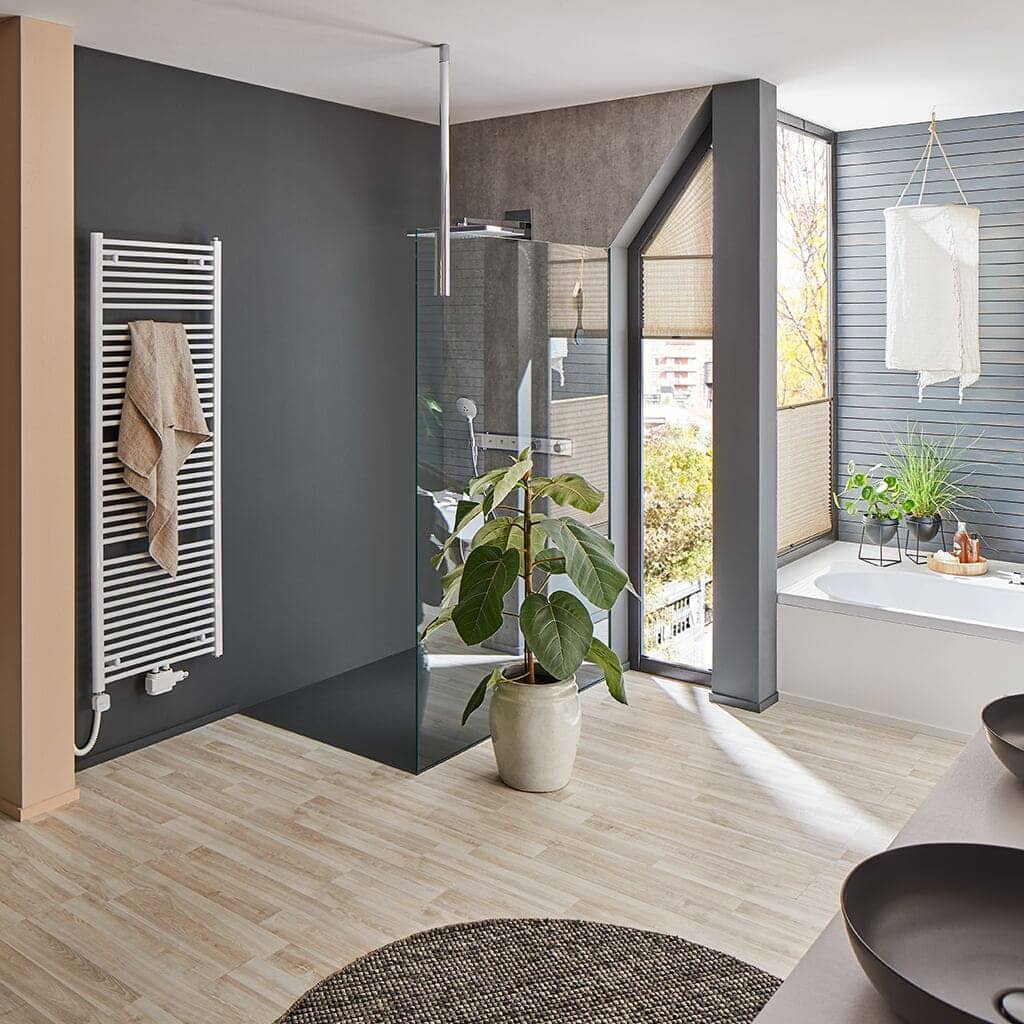 Weißer Gliederheizkörper in hellem Badezimmer mit Dusche