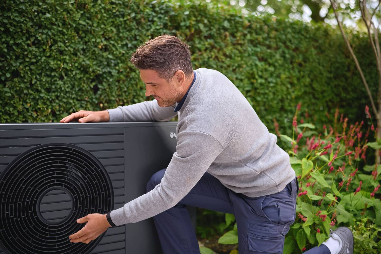 Techniker prüft eine moderne Wärmepumpe im Garten